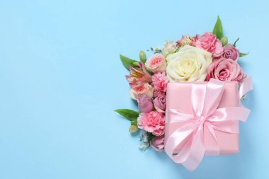 Hediye kutusu ve açık mavi arka planda güzel çiçekler. Metin için boşluk