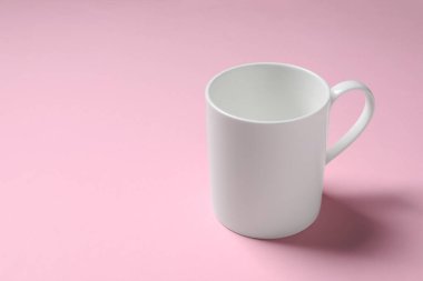 Pembe arka planda beyaz seramik bardak. Metin için boşluk