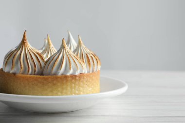 Lezzetli tatlı. Beyaz ahşap masada kremalı tart, yakın plan. Metin için boşluk