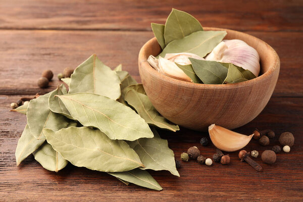 Aromatic bay leaves and spices on wooden table, closeup