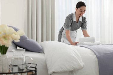 Genç hizmetçi havlu yığını otel Oda üzerine koyarak