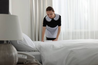 Genç hizmetçi otel odasında yatak yapma