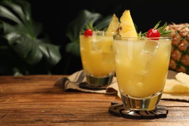 Ahşap masada biberiyeli ve kirazlı bir bardak lezzetli ananas kokteyli. Metin için boşluk