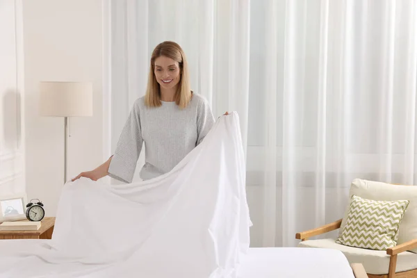 Woman changing bed linens at home. Space for text