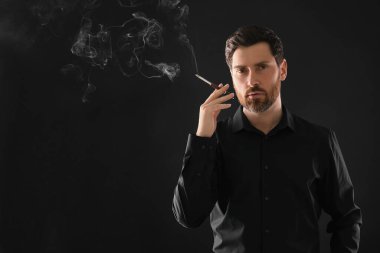 Siyah arka planda sigara içmek için sigara tutacağı, metin için boşluk kullanan adam