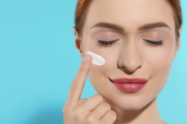 Yüzünde açık mavi arka planda güneş kremi olan genç ve güzel bir kadın. Yakın plan. Metin için boşluk