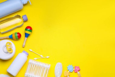 Sarı zemin üzerinde bebek bakım ürünleri ve aksesuarları ile düz konum, metin için boşluk