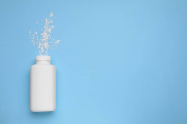Açık mavi zemin üzerinde şişe ve dağınık toz tozu, üst görünümü metin için alan. Bebek kozmetik ürünü