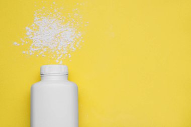 Sarı arka planda şişe ve toz alma tozu. Üstü açık, yazı için yer var. Bebek kozmetik ürünü