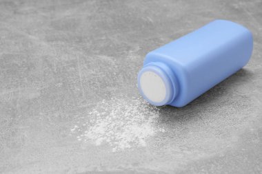 Gri masa üzerinde şişe ve dağınık bebek pudrası, metin için boşluk