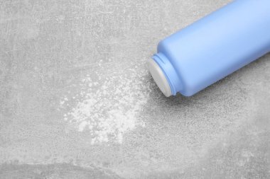 Gri masa üzerinde şişe ve dağınık bebek pudrası, üst görünümü metin için alan