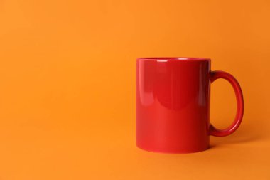Turuncu arka planda bir kırmızı seramik bardak. Metin için boşluk
