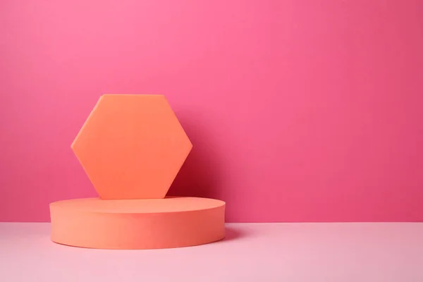 Geometric figures on table against pink background, space for text. Stylish presentation for product