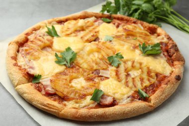 Gri masada maydanozlu lezzetli ananaslı pizza, yakın plan.