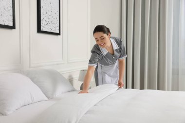 Genç hizmetçi otel odasında yatak yapma