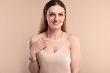 Bej arka planda zarif mücevherleri olan güzel bir kadın.