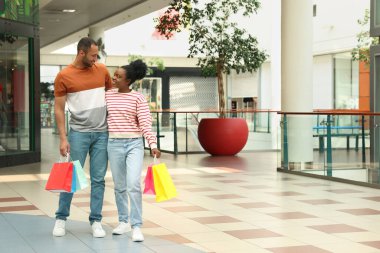 Family shopping. Happy couple with colorful bags in mall