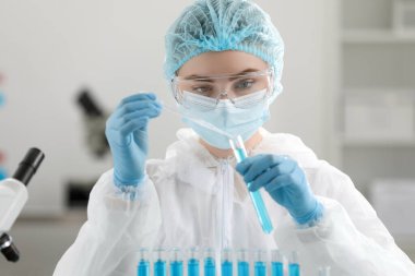 Laboratuvarda test tüpüne örnek damlatan bir bilim adamı.