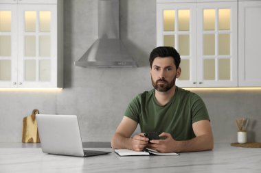 Asker mutfaktaki beyaz mermer masada akıllı telefon kullanıyor. Askerlik.