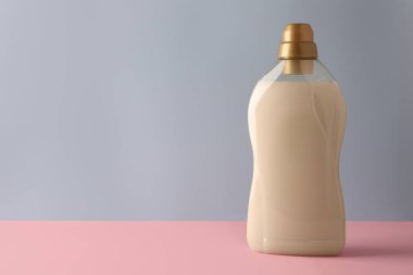 Açık gri arkaplan, metin için alan Pembe masa üzerinde bir şişe yumuşatıcı