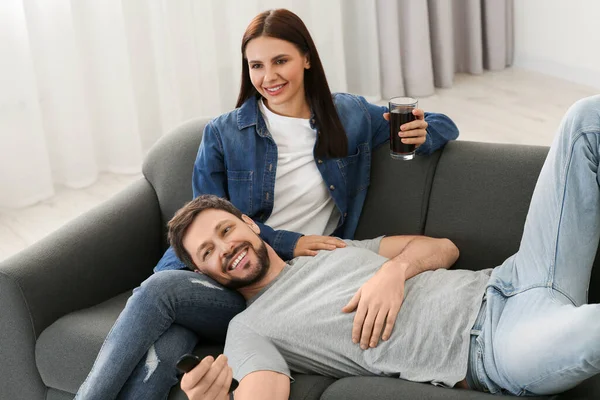 Happy couple watching show at home. Man changing TV channels with remote control
