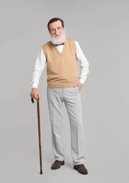 Starszy Mężczyzna Chodzącą Laską Jasnoszarym Tle — Zdjęcie stockowe
