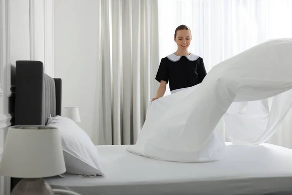 ホテルの部屋でベッドを作る若いメイド テキストのためのスペース — ストック写真