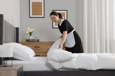Otel odasında yatak yapma genç Oda hizmetçisi