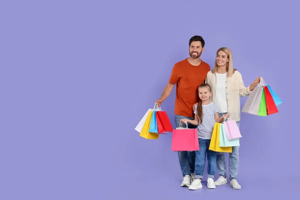家庭购物 快乐的父母和女儿 背景是紫罗兰色的许多彩色包包 案文的篇幅 — 图库照片