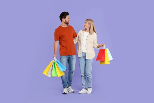 Familieneinkauf Glückliches Paar Mit Vielen Bunten Taschen Auf Violettem Hintergrund — Stockfoto