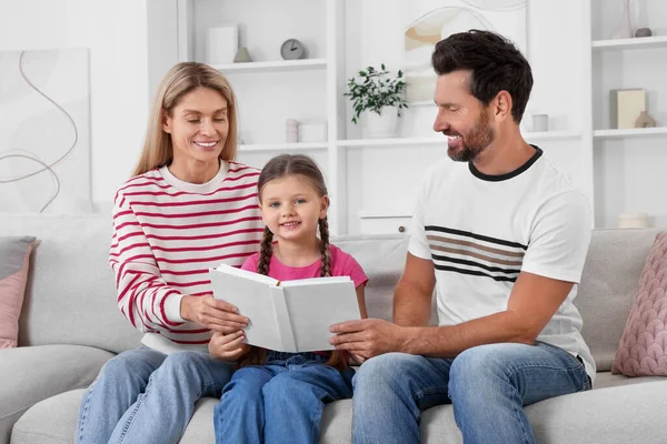 自宅でソファーで一緒に本を読んで幸せな家族 — ストック写真