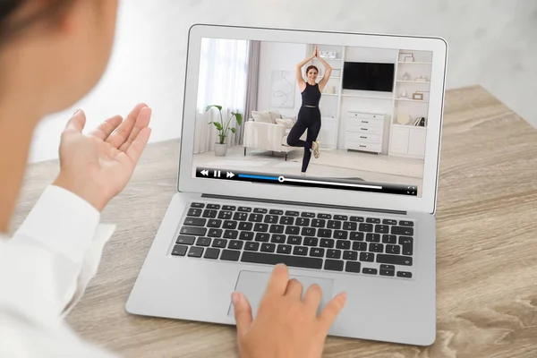 stock image Woman watching morning exercise video on laptop at table, closeup