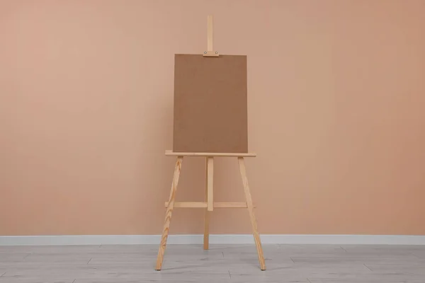 stock image Wooden easel with blank board near beige wall indoors