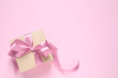 Pembe arka planda fiyonklu güzel bir hediye kutusu, üst manzara. Metin için boşluk