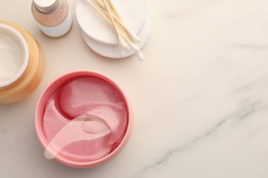 Beyaz mermer masa üzerinde kaşık ve kozmetik ürünlerle dolu bir kavanoz dolusu göz altı bandı. Metin için boşluk