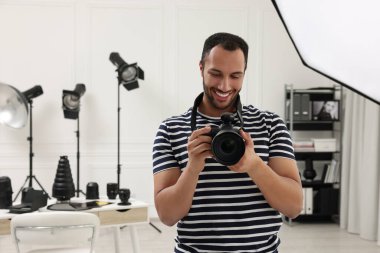 Modern fotoğraf stüdyosunda kamerası olan genç profesyonel fotoğrafçı.