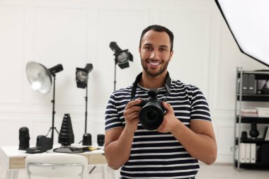 Modern fotoğraf stüdyosunda kamerası olan genç profesyonel fotoğrafçı.