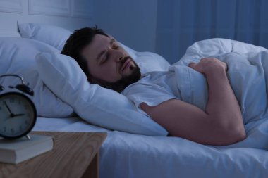 Geceleri yatakta uyuyan yakışıklı adam.