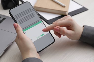 Elektronik imza. Beyaz ahşap masada cep telefonu kullanan bir kadın.