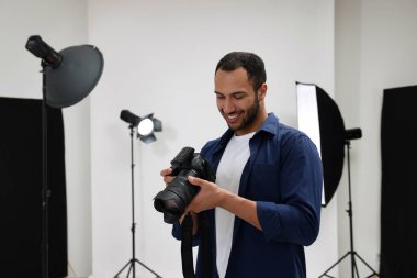 Modern fotoğraf stüdyosunda kamerası olan genç profesyonel fotoğrafçı.