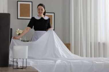 Genç hizmetçi otel odasında yatak yapma. Metin için yer