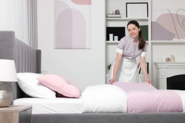 Genç hizmetçi otel odasında yatak yapma