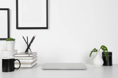 Ev işyerinde. Laptop, kırtasiye ve ev bitkileri beyaz ahşap masada.