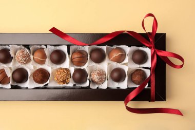 Bej masa üzerinde nefis çikolata şekerleri olan bir kutu, üst manzara.