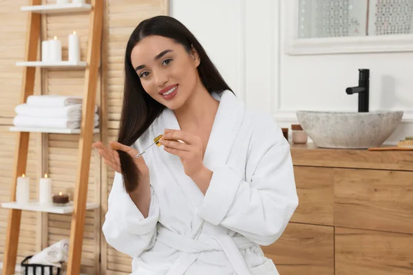 バスルームで髪にエッセンシャルオイルを適用幸せな若い女性 — ストック写真
