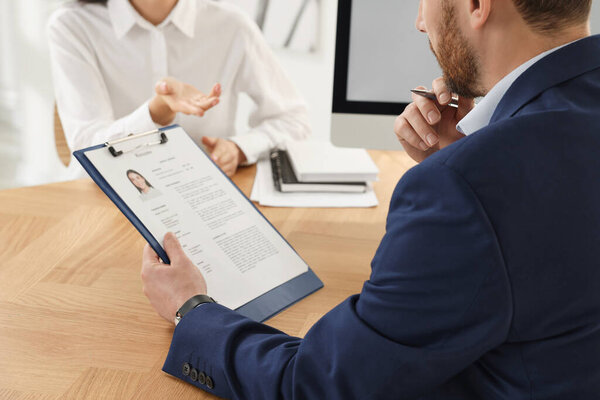 Human resources manager reading applicant's resume in office, closeup