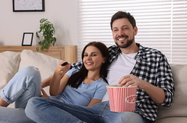 一对快乐的夫妇在家里看演出 使用遥控装置更换电视频道的妇女 — 图库照片