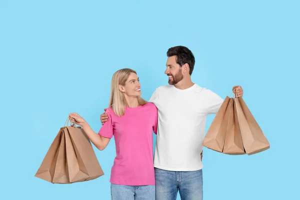 Familieneinkauf Glückliches Paar Mit Vielen Papiertüten Auf Hellblauem Hintergrund — Stockfoto