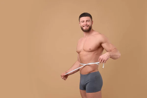 Lachende Atletische Man Meten Taille Met Tape Bruine Achtergrond Ruimte — Stockfoto