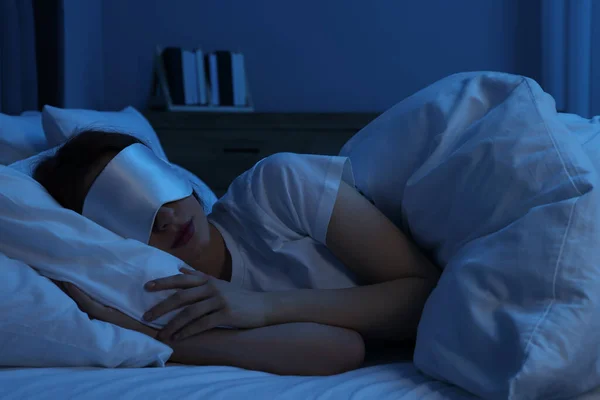 夜にベッドで寝ているマスクを持つ女性 — ストック写真